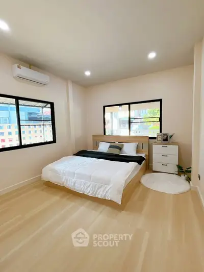 Spacious bedroom with modern decor and large windows offering natural light.