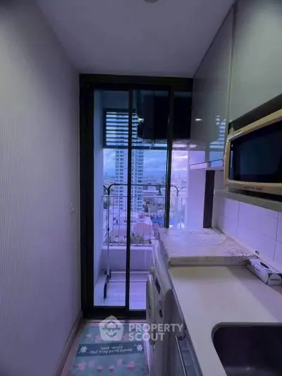 Compact kitchen with modern appliances and balcony view in urban apartment