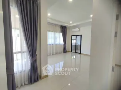 Spacious and bright living room with elegant curtains and modern lighting.
