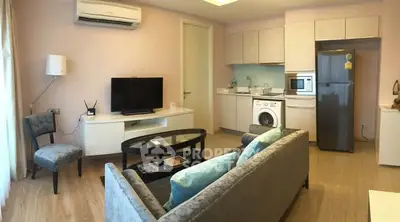 Modern living room with open kitchen, featuring sleek appliances and cozy seating area.