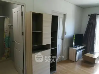 Modern living room with wooden furniture and TV, adjacent to bathroom.
