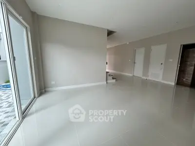 Spacious modern living room with large windows and sleek tile flooring