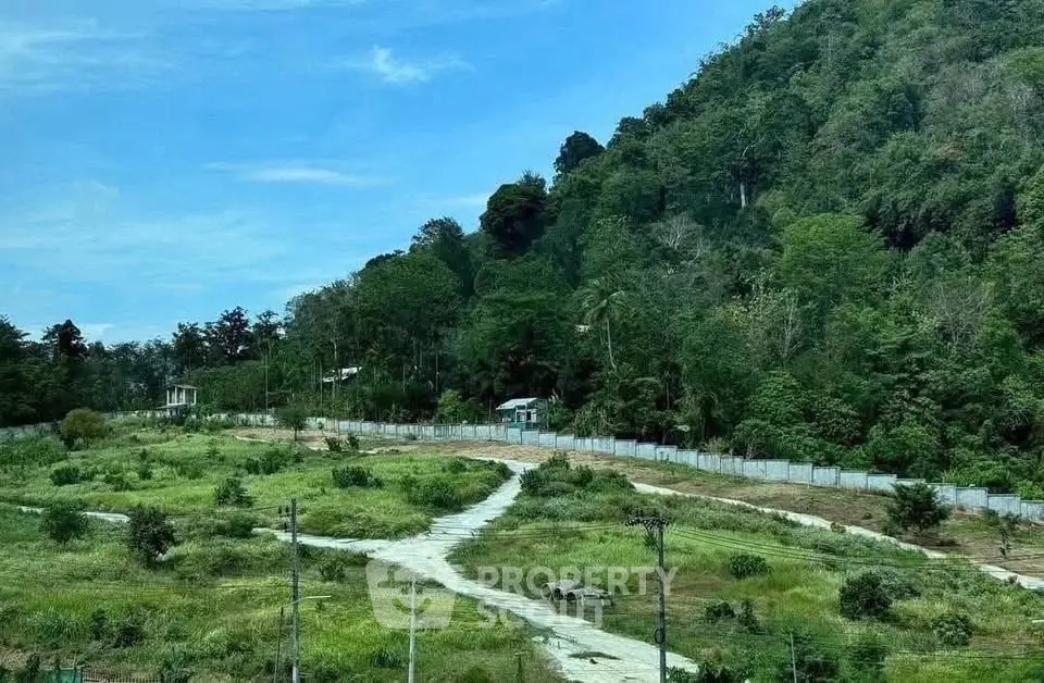 Scenic land plot with lush greenery and mountain backdrop, ideal for development opportunities.