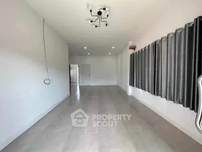 Spacious empty room with modern lighting and large windows, perfect for customization.
