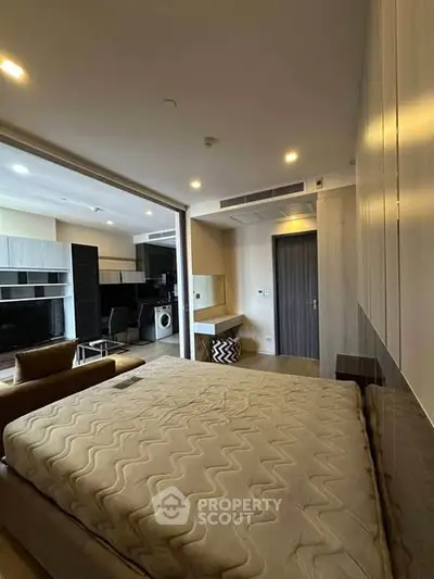 Modern studio apartment with open layout, featuring a cozy bed, sleek kitchen, and stylish living area.