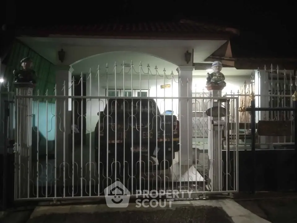 Charming single-story home with gated entrance and covered parking at night.