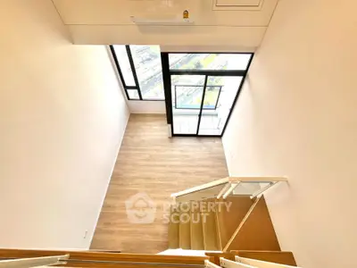 Spacious modern loft with large windows and wooden flooring, offering a bright and airy atmosphere.