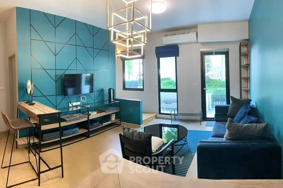 Modern living room with stylish decor, blue accent wall, and large window offering natural light.