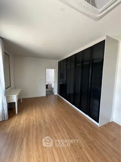 Spacious bedroom with sleek black wardrobe and wooden flooring