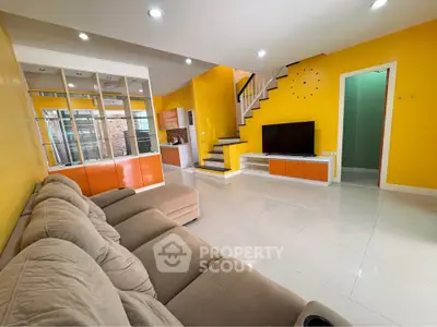 Spacious modern living room with vibrant yellow walls and stylish staircase