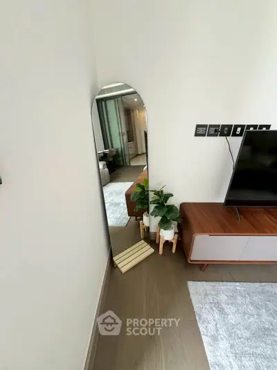 Modern living room with stylish furniture and decorative plants, featuring a sleek TV stand and elegant mirror.