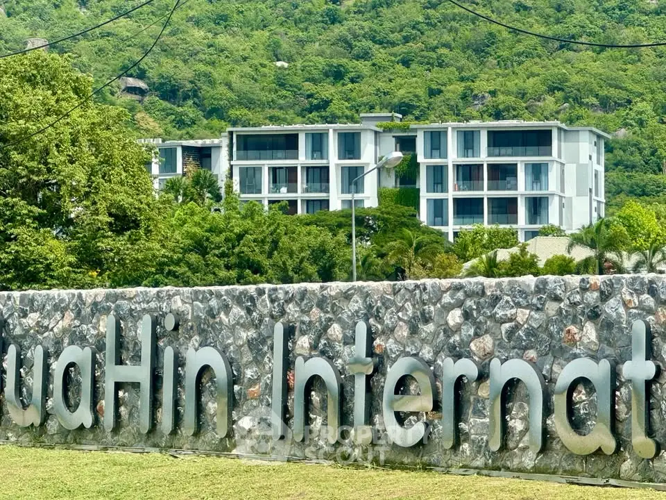 Luxurious modern building nestled in lush greenery with mountain backdrop, perfect for serene living.