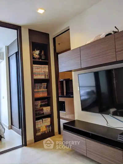 Modern living room with built-in shelving and flat-screen TV, showcasing sleek design and ample storage.
