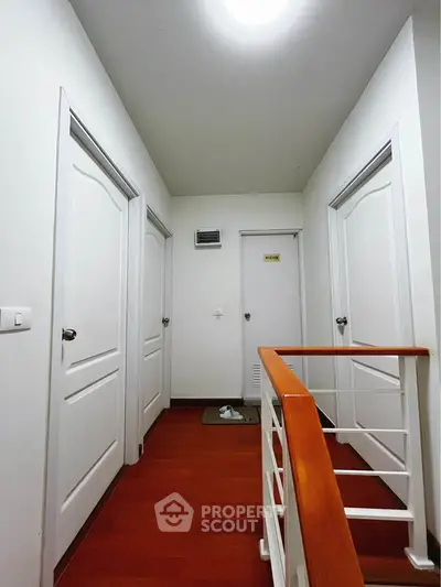 Modern hallway with wooden flooring and white doors in a stylish home interior.