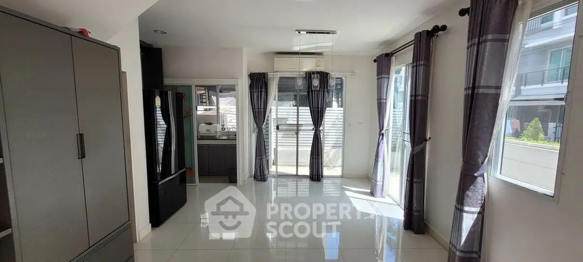 Spacious modern living room with large windows and sleek kitchen area