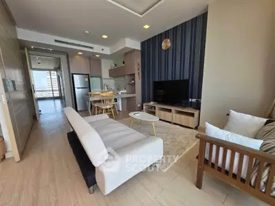 Modern living room with open kitchen, stylish decor, and natural light in a high-rise apartment.