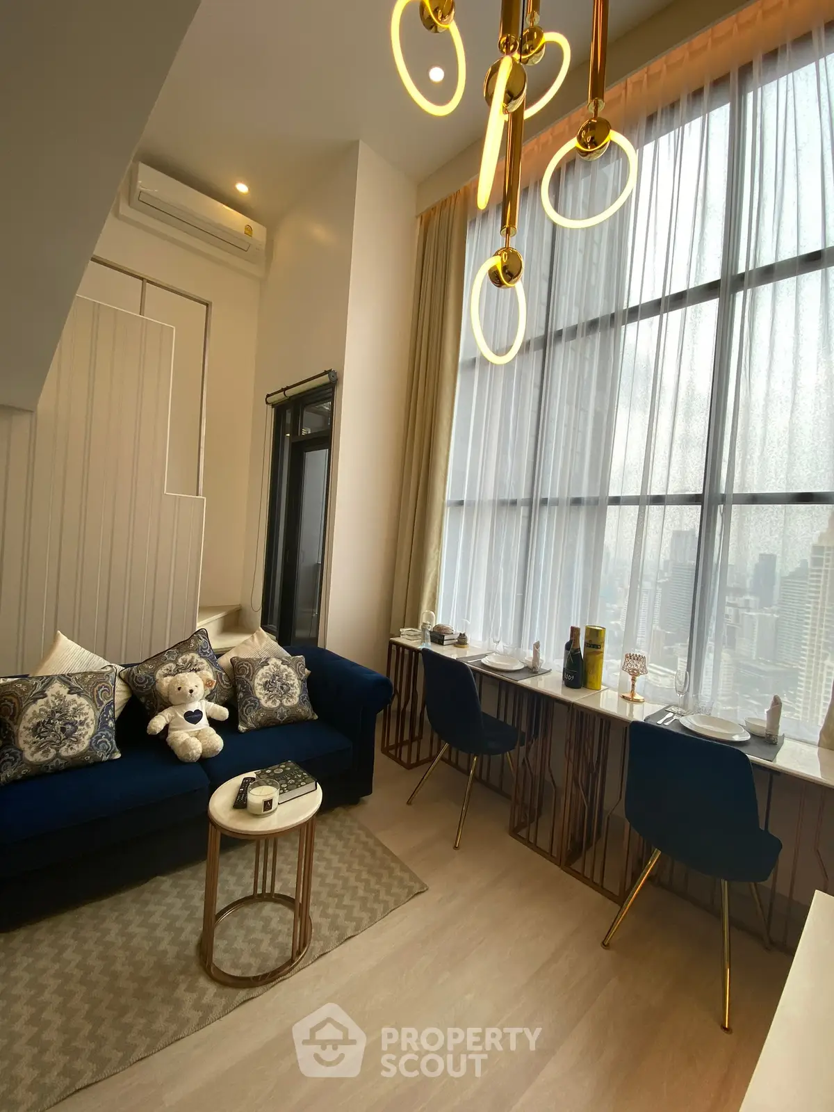 Modern living room with large windows, elegant lighting, and stylish decor in a high-rise apartment.