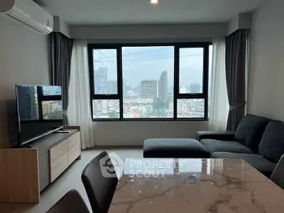 Modern living room with city view, featuring sleek furniture and large windows for natural light.