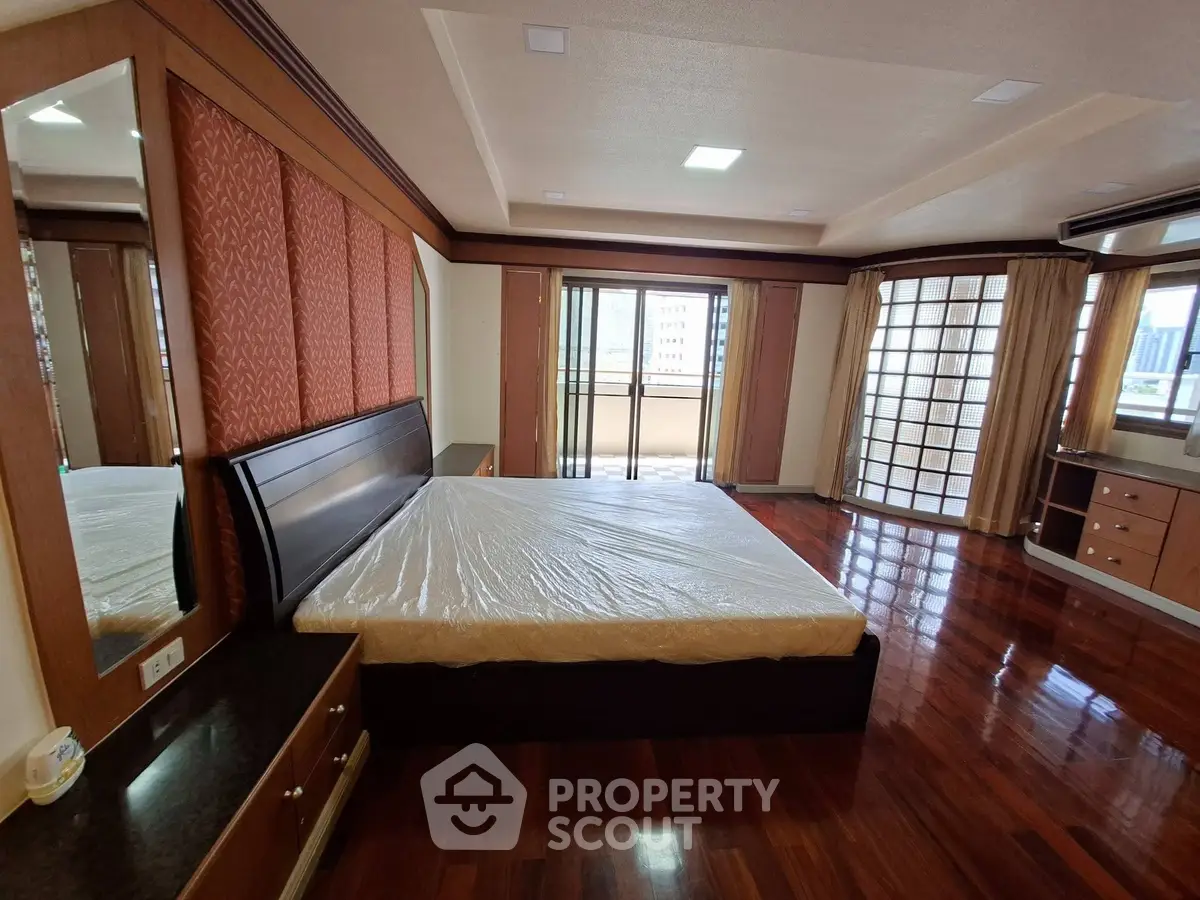 Spacious bedroom with elegant wooden flooring and large windows offering ample natural light.