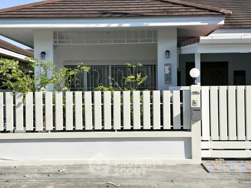 Charming single-story house with modern fence and lush greenery