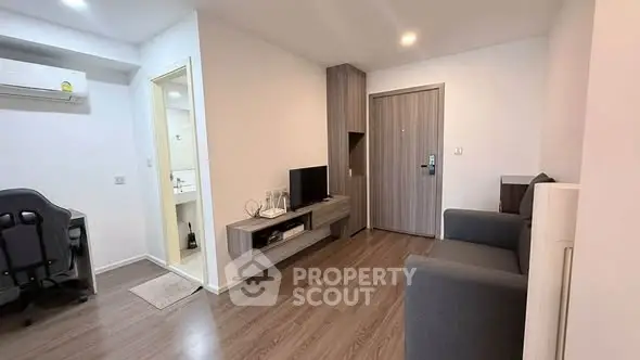 Modern living room with sleek design and wooden flooring, featuring a cozy sofa and wall-mounted TV.