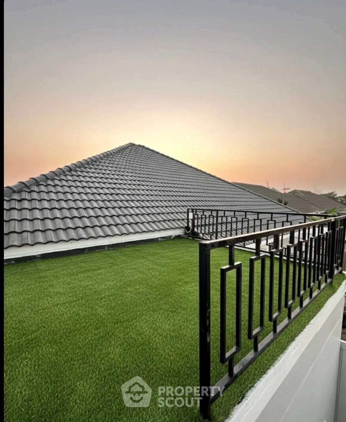 Stunning rooftop with artificial grass and modern railing at sunset