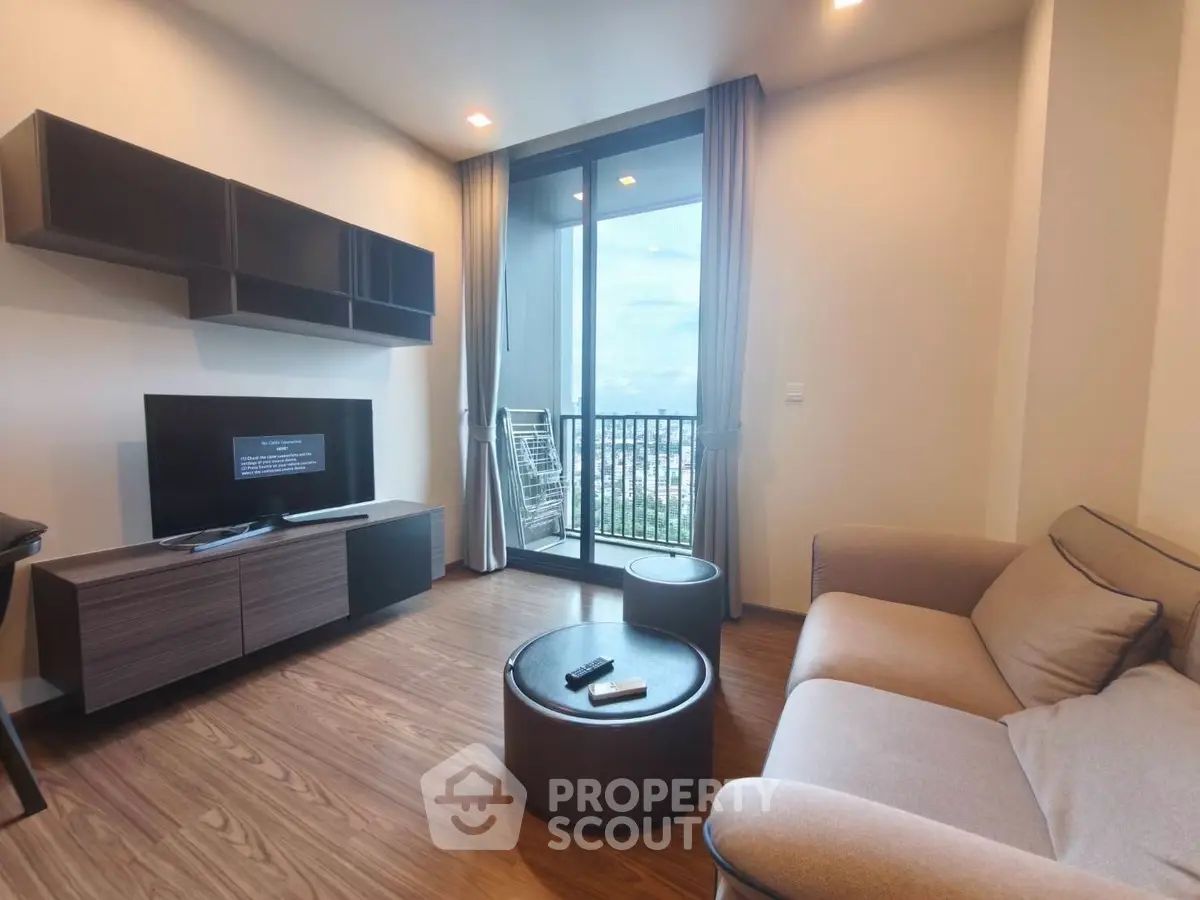 Modern living room with balcony view, stylish furniture, and sleek wooden flooring.