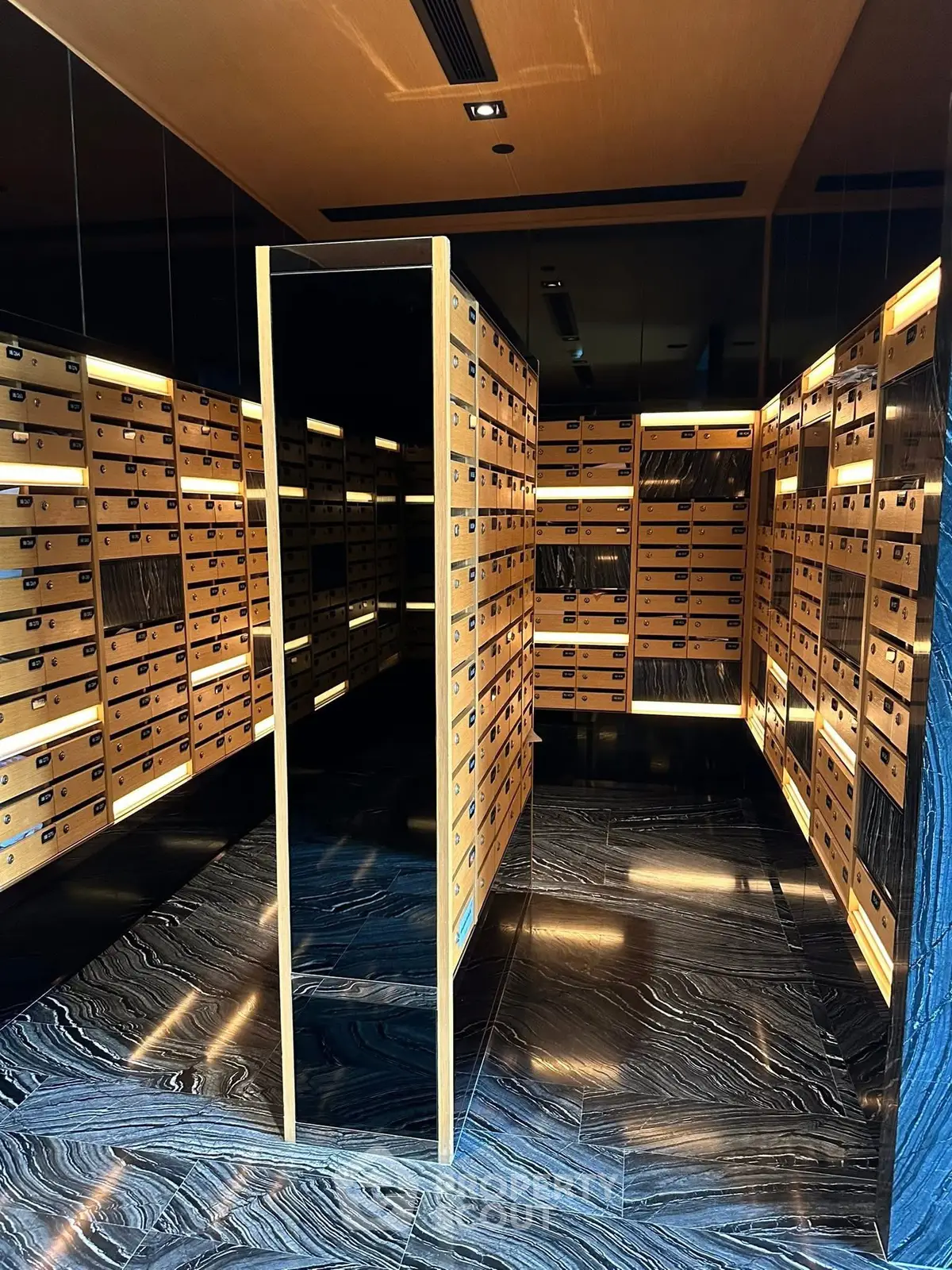 Luxurious modern mailroom with sleek wooden mailboxes and elegant lighting in a high-end residential building.