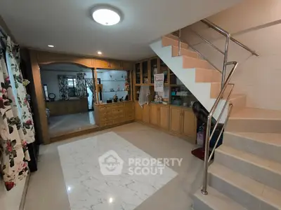 Spacious living area with elegant staircase and built-in wooden cabinets.