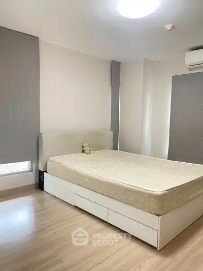 Spacious bedroom with modern design and natural light, featuring a comfortable bed and sleek flooring.
