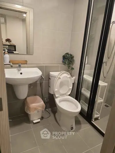 Modern bathroom with sleek fixtures and glass shower enclosure in a contemporary apartment.