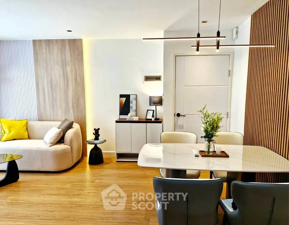 Modern living room with stylish decor and elegant dining area, featuring contemporary furniture and warm lighting.