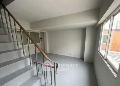 Spacious minimalist interior with staircase and large windows, perfect for modern living.