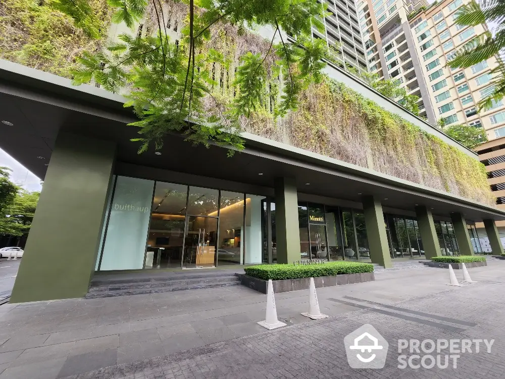 Modern building exterior with lush green facade and glass entrance in urban setting.