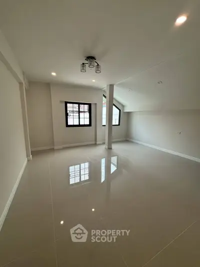 Spacious modern living room with large windows and sleek tile flooring, perfect for natural light and open living.