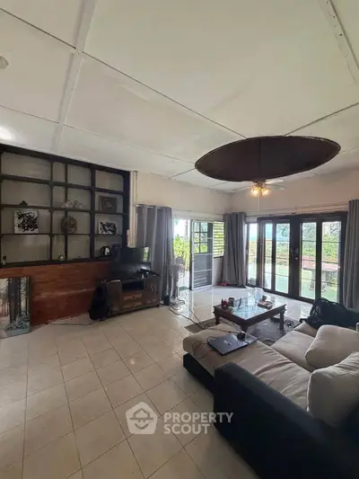 Spacious living room with large windows and garden view, featuring modern furniture and open layout.