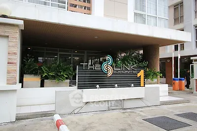 Modern building entrance with sleek design and lush greenery at The Link Sukhumvit.