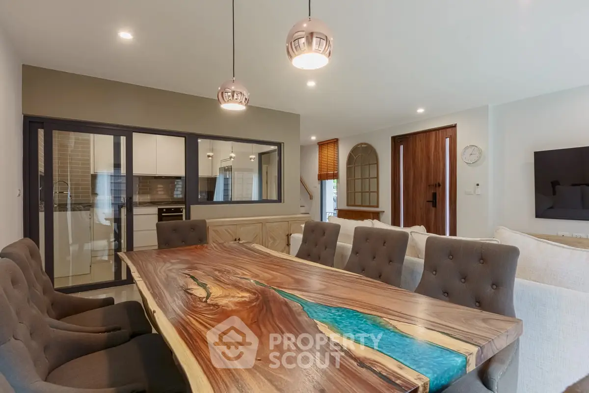 Stunning dining area with unique wooden table and modern lighting in open-concept living space.