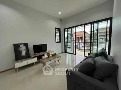 Modern living room with sleek furniture and large glass doors opening to a balcony.