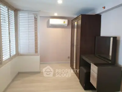 Spacious bedroom with modern wardrobe and vanity, featuring sleek wooden flooring and ample natural light.