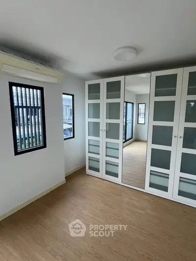 Spacious bedroom with large mirrored wardrobe and natural light