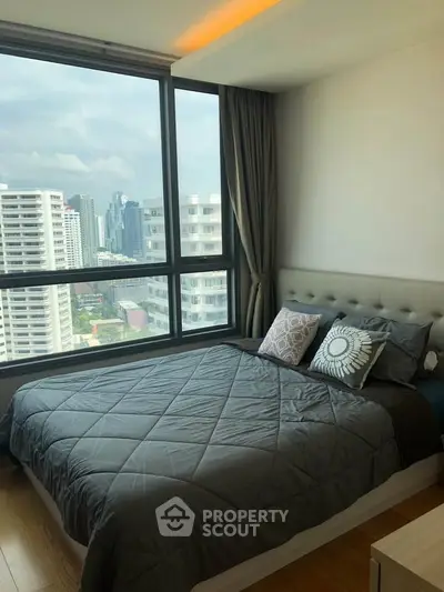 Modern bedroom with large window offering stunning city view in high-rise apartment