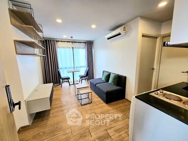 Modern living room with wooden flooring, cozy sofa, and dining area near window.