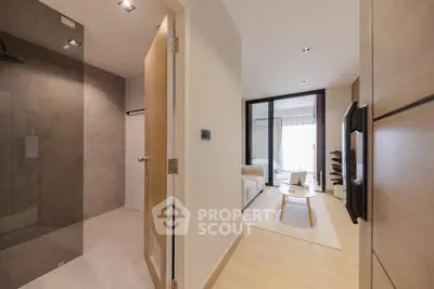 Modern apartment interior with open living room and bathroom entrance, featuring sleek design and natural lighting.