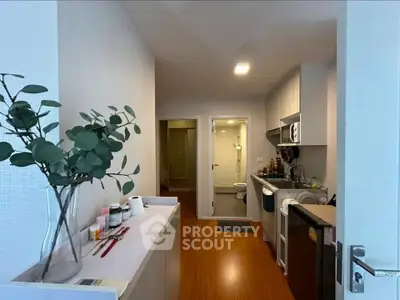 Modern kitchen with sleek appliances and wooden flooring in a cozy apartment setting.