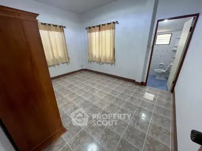 Spacious empty bedroom with tiled floor and natural light from two windows.