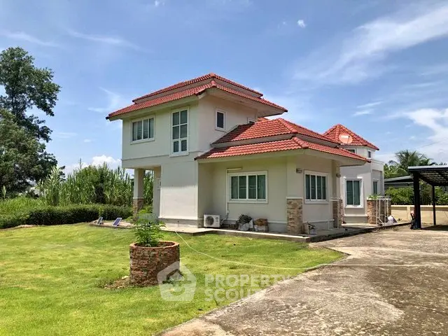 Charming two-story house with red roof and lush green lawn under a clear blue sky.