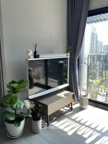 Modern living room with large TV, stylish decor, and balcony view in urban apartment.