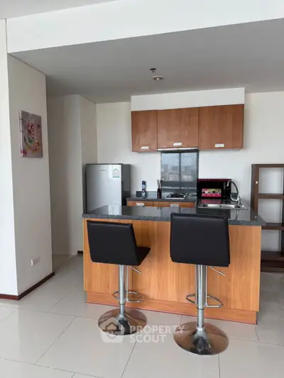Modern kitchen with island, bar stools, and sleek appliances in a stylish apartment.