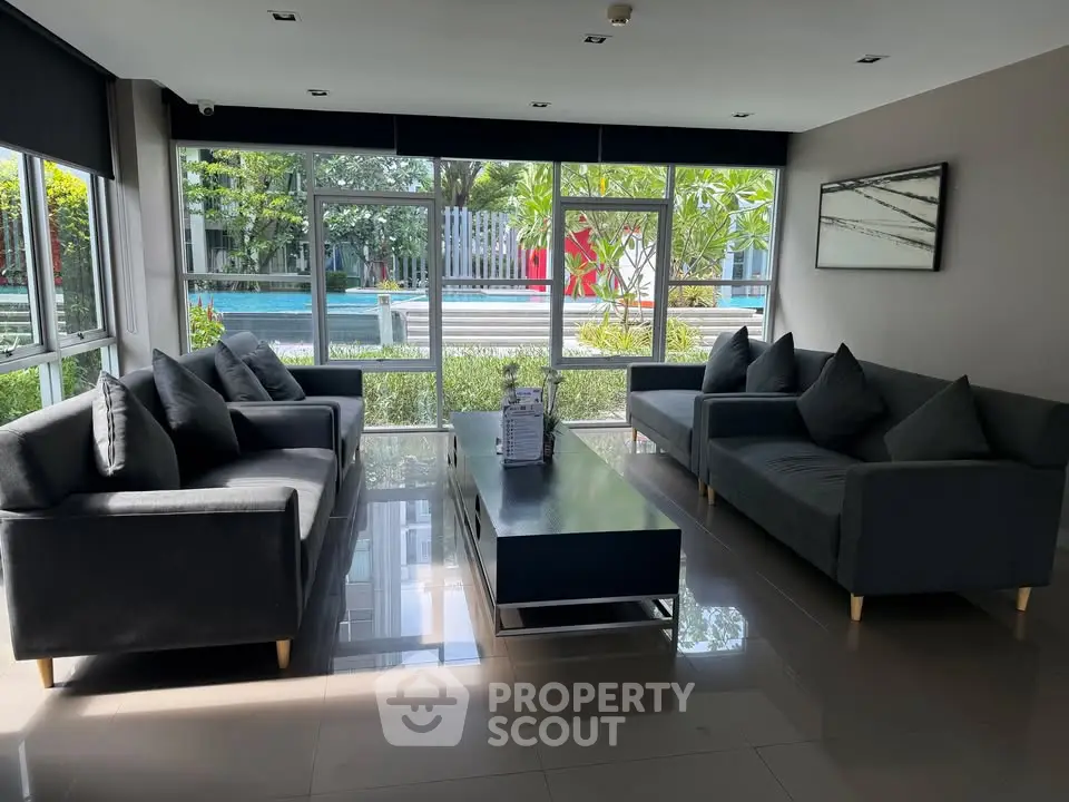 Spacious modern living room with large windows overlooking a lush garden and pool area.